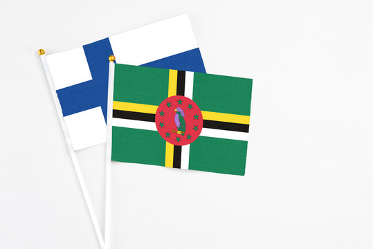 Dominica and Finland stick flags on white background. High quality fabric, miniature national flag. Peaceful global concept.White floor for copy space.