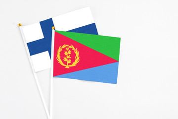 Eritrea and Finland stick flags on white background. High quality fabric, miniature national flag. Peaceful global concept.White floor for copy space.