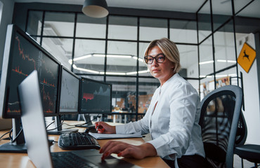 Female stockbroker in formal clothes works in the office with financial market