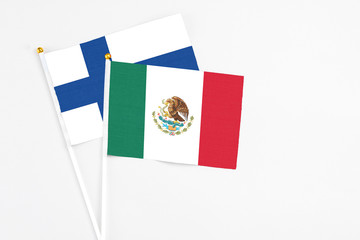 Mexico and Finland stick flags on white background. High quality fabric, miniature national flag. Peaceful global concept.White floor for copy space.