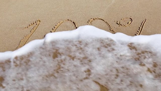 Handwritten inscription 100% on a sandy sea beach is washed by the sea wave with foam on a summer sunny day. Disappearing statistics and percent writing