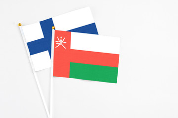 Oman and Finland stick flags on white background. High quality fabric, miniature national flag. Peaceful global concept.White floor for copy space.
