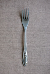 Metal fork on brown textile background