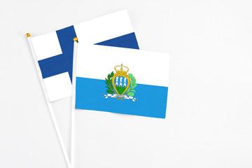 San Marino and Finland stick flags on white background. High quality fabric, miniature national flag. Peaceful global concept.White floor for copy space.