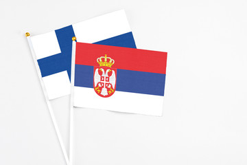 Serbia and Finland stick flags on white background. High quality fabric, miniature national flag. Peaceful global concept.White floor for copy space.