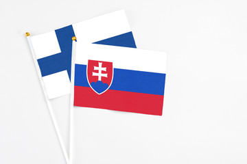 Slovakia and Finland stick flags on white background. High quality fabric, miniature national flag. Peaceful global concept.White floor for copy space.