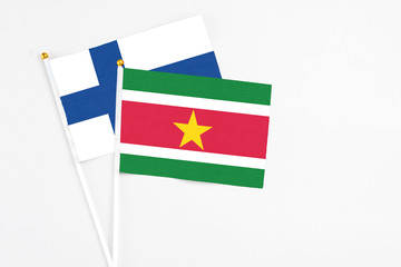 Suriname and Finland stick flags on white background. High quality fabric, miniature national flag. Peaceful global concept.White floor for copy space.