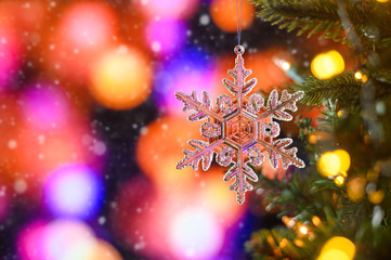 Fototapeta na wymiar Christmas toy on a Christmas tree a transparent star, on a bright colorful bokeh background, with falling snow. Horizontal frame