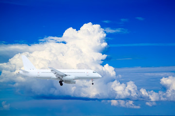 Obraz na płótnie Canvas white passenger plane comes in to land with natural background of white clouds and blue sky