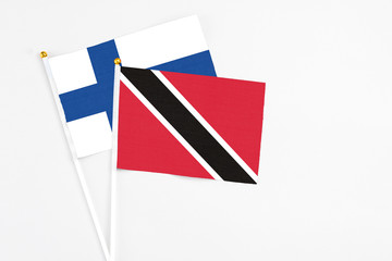 Trinidad And Tobago and Finland stick flags on white background. High quality fabric, miniature national flag. Peaceful global concept.White floor for copy space.