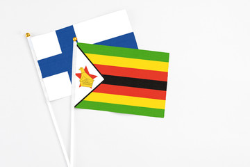 Zimbabwe and Finland stick flags on white background. High quality fabric, miniature national flag. Peaceful global concept.White floor for copy space.