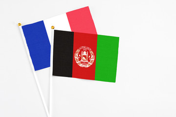 Afghanistan and France stick flags on white background. High quality fabric, miniature national flag. Peaceful global concept.White floor for copy space.
