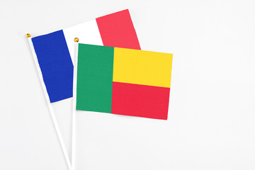 Benin and France stick flags on white background. High quality fabric, miniature national flag. Peaceful global concept.White floor for copy space.