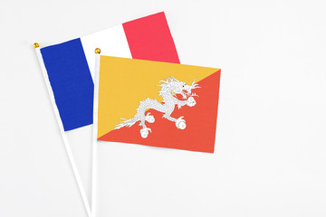 Bhutan and France stick flags on white background. High quality fabric, miniature national flag. Peaceful global concept.White floor for copy space.