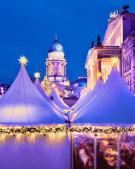 Fototapeta premium Romantic evening view of lit canvas tents and illuminated historical buildings of Chtristmas market in Gandarmenmarkt in Berlin, Germany at night.