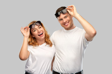 summer accessory, eyewear and people concept - portrait of happy couple in white t-shirts and sunglasses over grey background