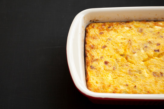 Homemade Cheesy Amish Breakfast Casserole On A Black Background, Low Angle View. Space For Text.