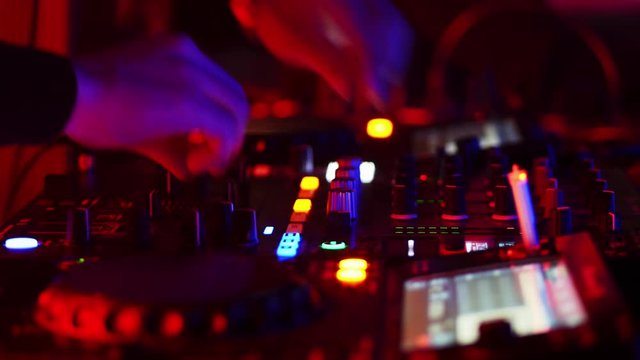 Close-up of DJ hands working on the remote control at night club