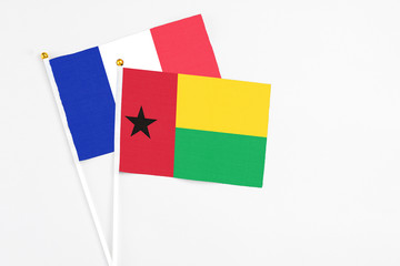 Guinea Bissau and France stick flags on white background. High quality fabric, miniature national flag. Peaceful global concept.White floor for copy space.