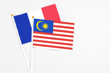 Malaysia and France stick flags on white background. High quality fabric, miniature national flag. Peaceful global concept.White floor for copy space.