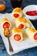 Pigs in a planket - puff pastry rolls with sausages on a wire rack.