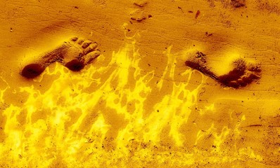 Two footprints in bright yellow sand