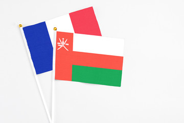 Oman and France stick flags on white background. High quality fabric, miniature national flag. Peaceful global concept.White floor for copy space.