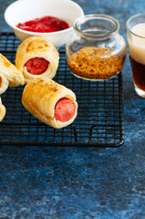 Pigs in a planket - puff pastry rolls with sausages on a wire rack.