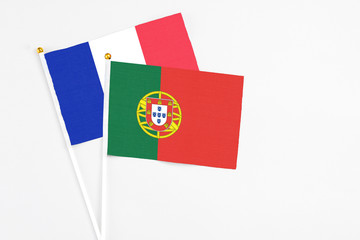 Portugal and France stick flags on white background. High quality fabric, miniature national flag. Peaceful global concept.White floor for copy space.