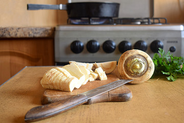 Slicing parsnip on a cutting board.