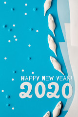 Creative paper flat lay in blue and white with marshmallow mice, snowflakes and paper number 2020. Text 