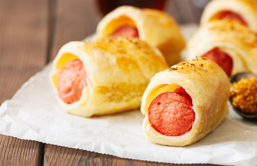 Pigs in a planket - puff pastry rolls with sausages on a wooden background.