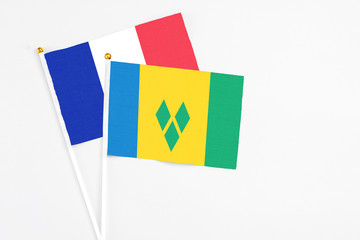 Saint Vincent And The Grenadines and France stick flags on white background. High quality fabric, miniature national flag. Peaceful global concept.White floor for copy space.