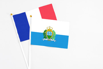 San Marino and France stick flags on white background. High quality fabric, miniature national flag. Peaceful global concept.White floor for copy space.