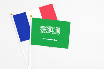 Saudi Arabia and France stick flags on white background. High quality fabric, miniature national flag. Peaceful global concept.White floor for copy space.