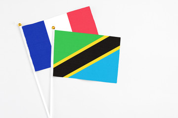 Tanzania and France stick flags on white background. High quality fabric, miniature national flag. Peaceful global concept.White floor for copy space.