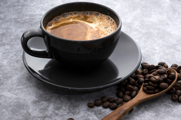 Hot coffee and coffee beans on a concrete background