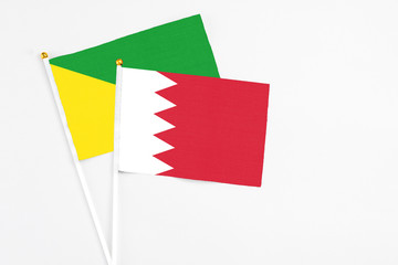 Bahrain and French Guiana stick flags on white background. High quality fabric, miniature national flag. Peaceful global concept.White floor for copy space.