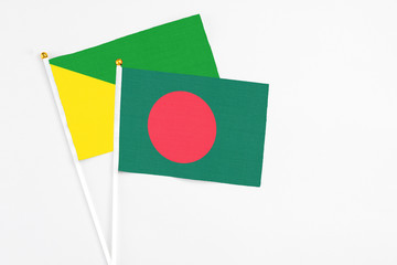 Bangladesh and French Guiana stick flags on white background. High quality fabric, miniature national flag. Peaceful global concept.White floor for copy space.