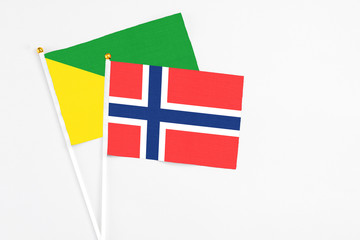 Obraz premium Bouvet Islands and French Guiana stick flags on white background. High quality fabric, miniature national flag. Peaceful global concept.White floor for copy space.
