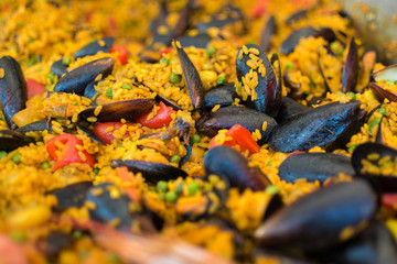 Paella traditional Spanish rice dish with seafood peas saffron bell pepper mussels close up depth of field contrast yellow rice