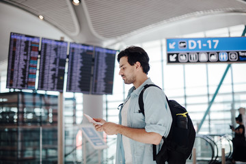 The guy at the airport waiting for departure, looking schedule.