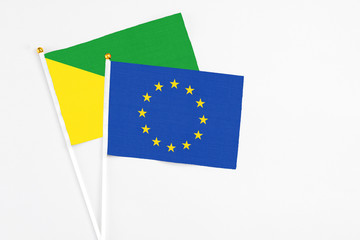 European Union and French Guiana stick flags on white background. High quality fabric, miniature national flag. Peaceful global concept.White floor for copy space.