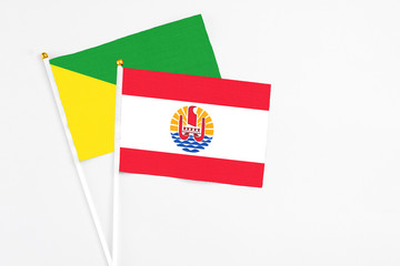 French Polynesia and French Guiana stick flags on white background. High quality fabric, miniature national flag. Peaceful global concept.White floor for copy space.