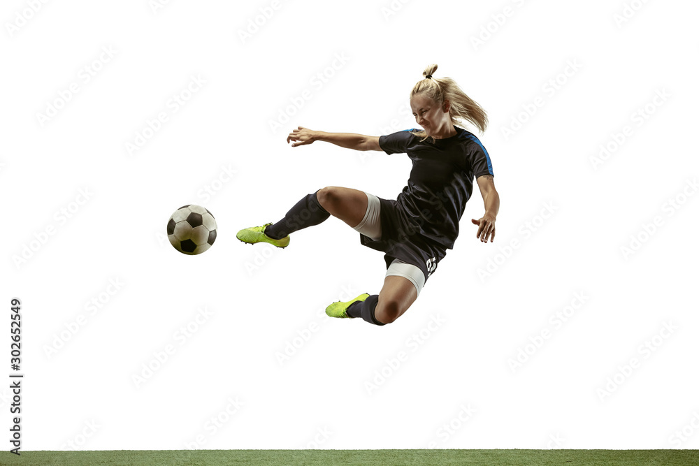 Wall mural Young female soccer or football player with long hair in sportwear and boots kicking ball for the goal in jump on white background. Concept of healthy lifestyle, professional sport, motion, movement.