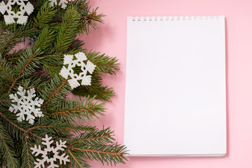 christmas wish list on pink background with fir branches and snowflakes, copy space