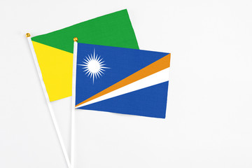 Marshall Islands and French Guiana stick flags on white background. High quality fabric, miniature national flag. Peaceful global concept.White floor for copy space.