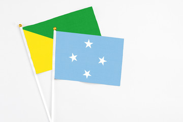 Micronesia and French Guiana stick flags on white background. High quality fabric, miniature national flag. Peaceful global concept.White floor for copy space.
