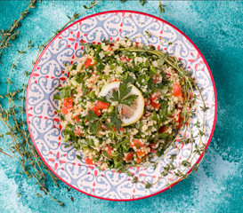 Tabule salad of bulgur, tomatoes, spices, dill on a blue background. Traditional oriental cuisine.