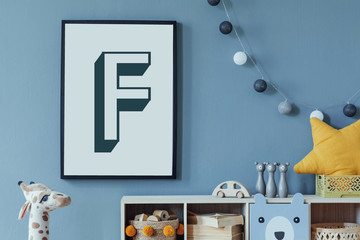 Stylish scandinavian newborn baby room with wooden cabinet, toys, mock up poster frame and children's accessories. Modern interior with eucalyptus background wall and cottona balls. Modern home decor. © FollowTheFlow